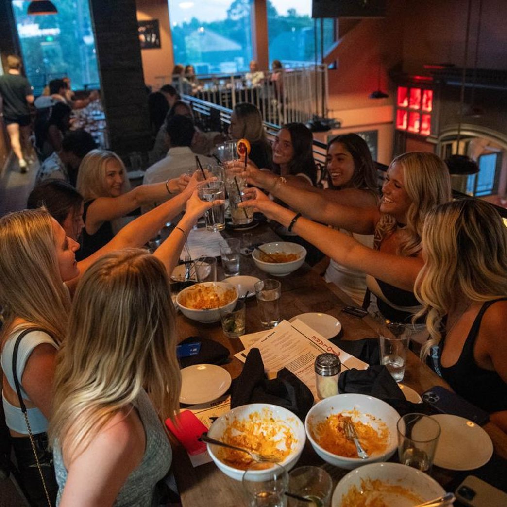 Group of people toasting with drinks at a table with empty plates