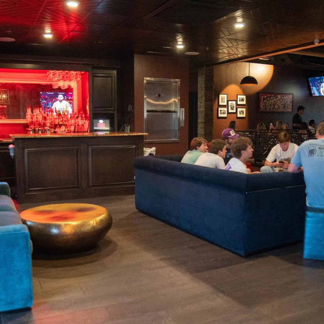 Lounge area with a bar sofas guests and TVs