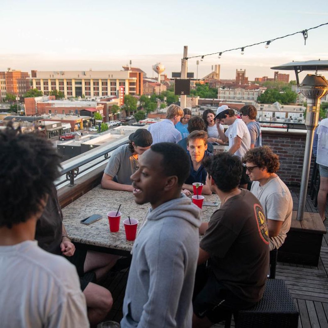 People socializing on a rooftop patio with cityscape in the background